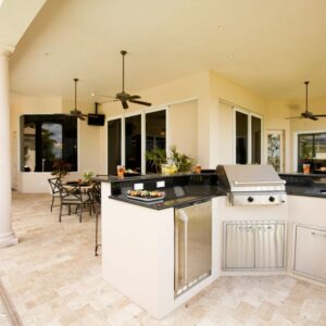 Outdoor kitchen area with stainless steel appliances and ceiling fans.