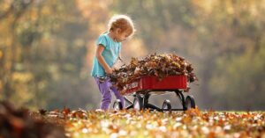 young girl pulling fall leaves in a wagon