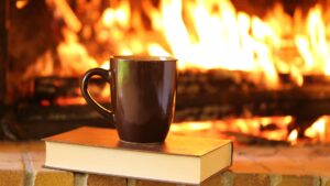 book and mug next to a fireplace