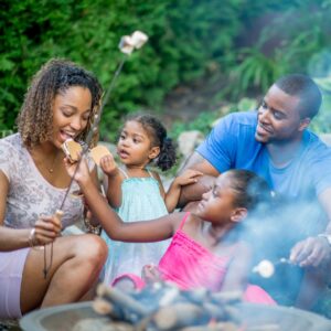 family sharing smores around an outdoor fireplace