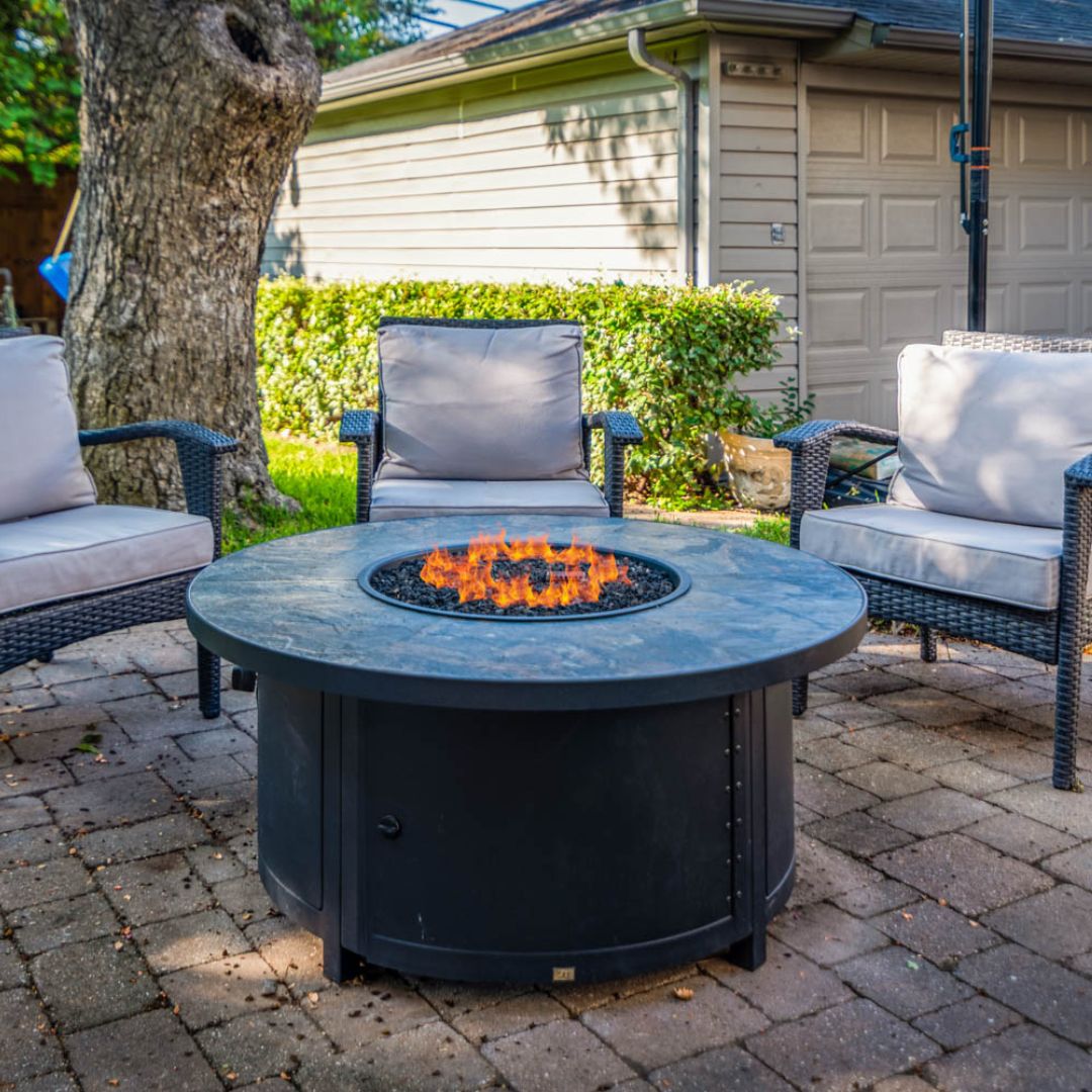 An outdoor fire pit emitting flames, surrounded by chairs