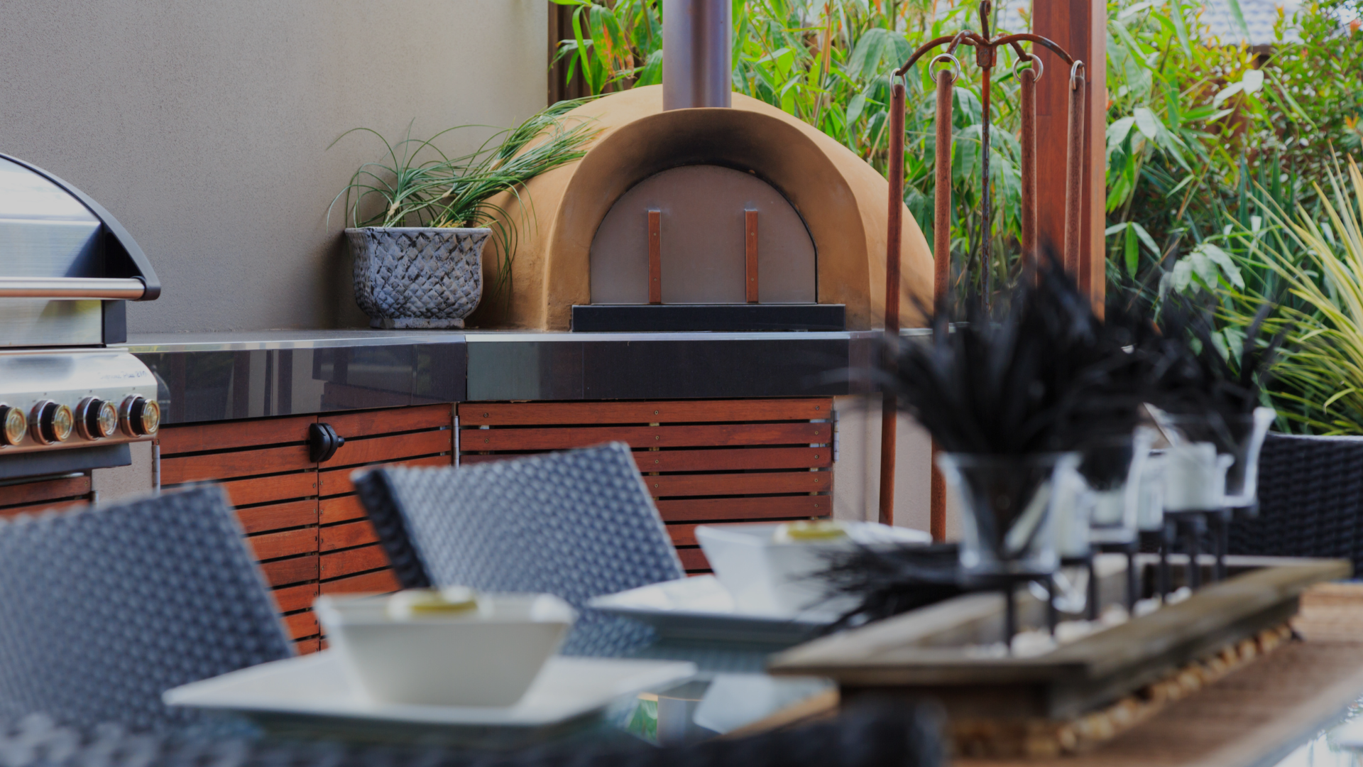 A nice outdoor kitchen with a woodfire stove and ample counterspace as well as a dining table.