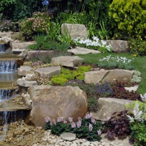 A water feature trickling over stones in a backyard.