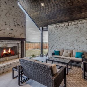 A covered outdoor patio with seating and a stainless steel outdoor fireplace.