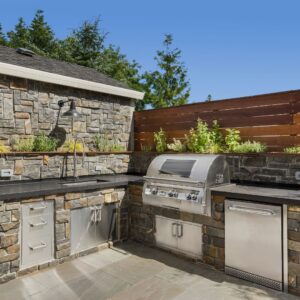 Outdoor kitchen with grill and lighting above counters